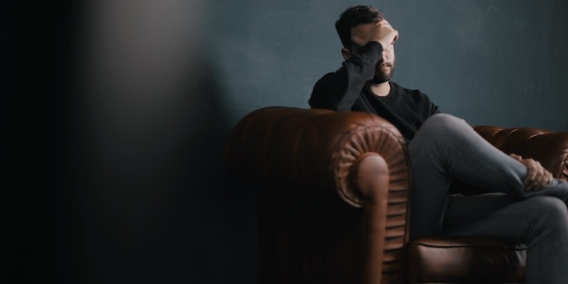 man-on-brown-leather-sofa-looking-forlorn